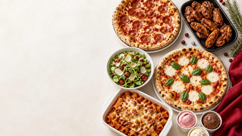 Holiday party catering spread with hand-tossed pizzas, oven-fired wings, fresh salad, baked pasta and gelato on a bright festive table